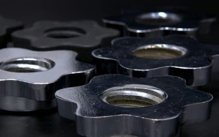 Close-up of several metallic, flower-shaped nuts with central holes, arranged on a dark surface. Their reflective silver surfaces and rugged texture highlight the quality components used in industrial gearbox rebuild projects.