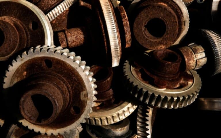 A close-up view of several rusty metal gears and cogs, piled together in a disorderly fashion, showing textured surfaces and worn teeth—ideal for showcasing industrial gearbox repair or gearbox rebuild services.