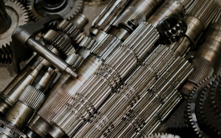 A close-up view of interlocking metal gears and shafts, highlighting the intricate details and textures of mechanical parts found in machinery—ideal for showcasing industrial gearbox repair or gearbox rebuild services.