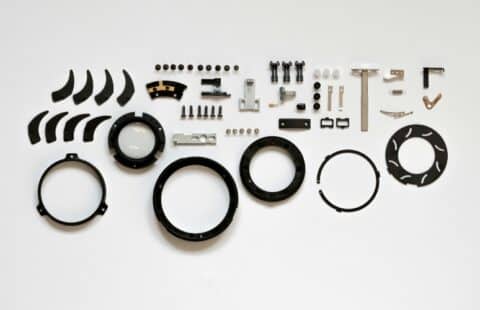 Pieces of a gearbox taken apart and laid out on a white background.