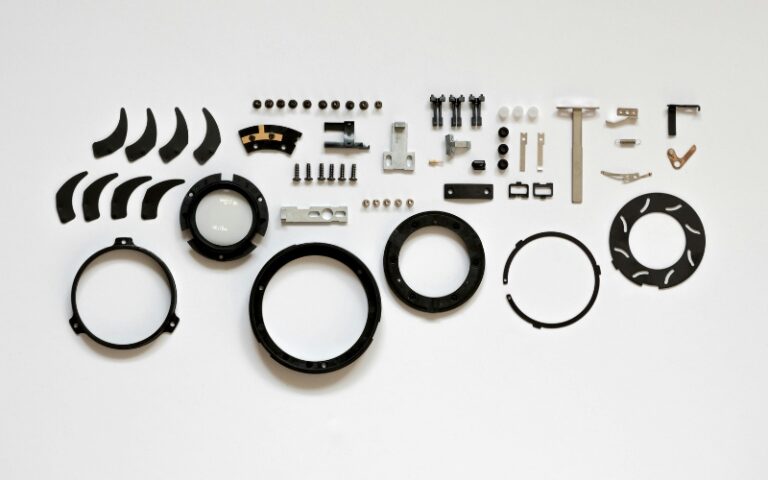 Various small mechanical parts, gears, and circular components neatly arranged on a white background, illustrating the intricate pieces involved in an industrial gearbox repair or emergency gearbox repair.
