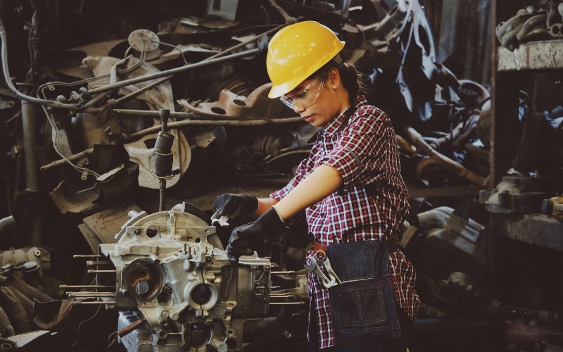 A technician works on an engine wearing a yellow hard-hat